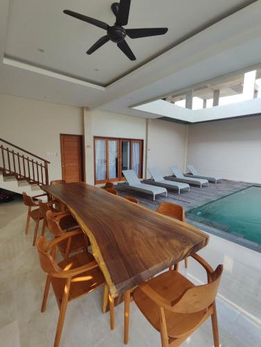 a dining room with a table and chairs and a swimming pool at Villa Lovecho in Canggu
