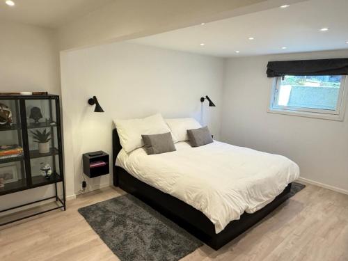 a bedroom with a bed with white sheets and a window at Idyllic Island Home 15 Min from Oslo in Asker