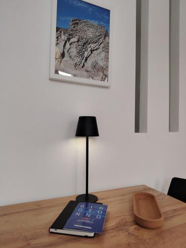 a book sitting on top of a table with a lamp at Casa Fiorenza - Da e Nònne in Carloforte