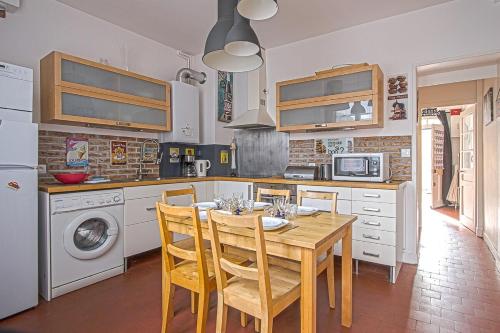 Il comprend une cuisine avec une table et des chaises en bois. dans l'établissement Le Petit Versailles, à Fécamp