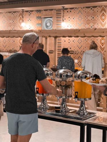 a man standing in front of a bar preparing drinks at Wadi rum camp hamod in Wadi Rum