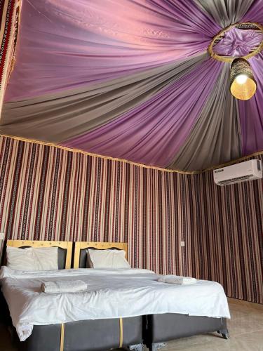 a room with a bed with a purple ceiling at Wadi rum camp hamod in Wadi Rum