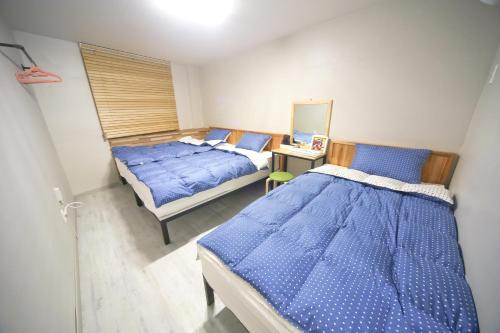 a bedroom with two beds with blue sheets at Ganse Guesthouse in Jeju