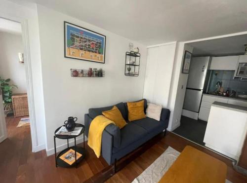 un salon avec un canapé bleu avec des coussins jaunes dans l'établissement PARIS CENTER Charming apartment - Strasbourg Saint Denis, à Paris