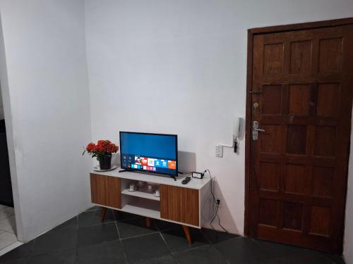 a television sitting on a cabinet in a room with a door at APARTAMENTO de 1 QUARTO JARDIM CAMBURI ,VITÓRIA-ES in Vitória