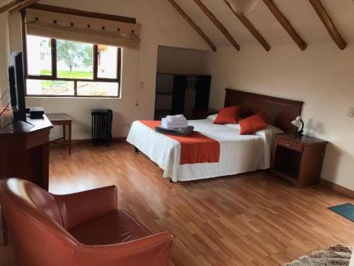 a bedroom with a bed with orange pillows and a television at hotel el portal de las Flores, Alojamiento Rural in Chía