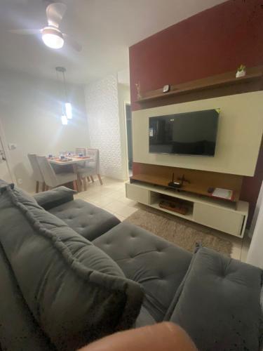 a living room with a couch and a flat screen tv at Apartamento com AR Condicionado, Condomínio aconchegante com piscina 2 Qts in Serra