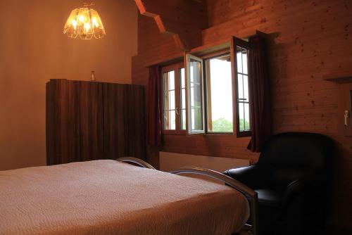 a bedroom with a bed and a chair and a window at The Saxeten alps in Arni Alp