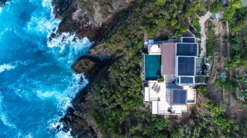 an aerial view of a house on a cliff next to the ocean at House of Rogues in Tortola Island