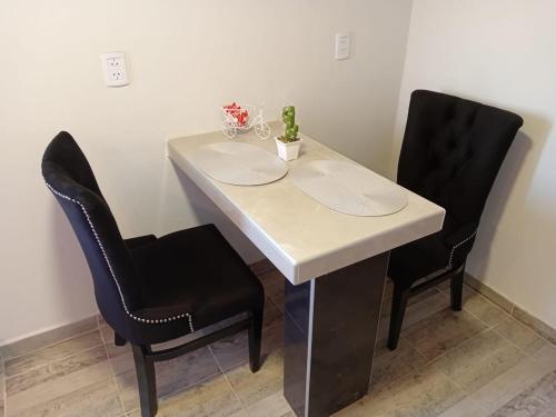a table with two black chairs and a white table at Cafayate suite in Cafayate