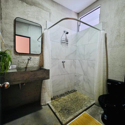 a bathroom with a shower with a sink and a mirror at Vibes Wellness House in Tamanique