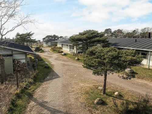 a dirt road next to a house with a tree at Holiday home on a holiday park in Gilleleje in Gilleleje