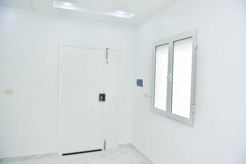 a white bathroom with a mirror and a window at Beau séjour in Bin Rhilouf