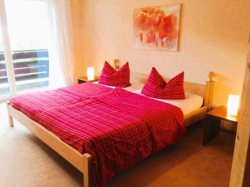 a bedroom with a large bed with red pillows at Haus an der Therme in Bad Endorf