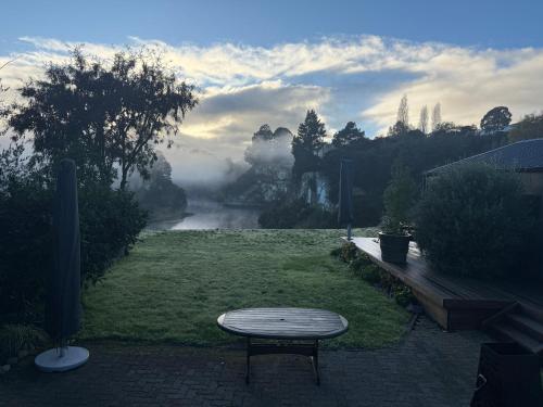 a table and a bench in a field with a foggy river at Sugar Cliff Vista Couples Retreat in Taupo