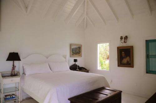 a white bedroom with a large bed and a window at Lowena Cottage in Tortola Island