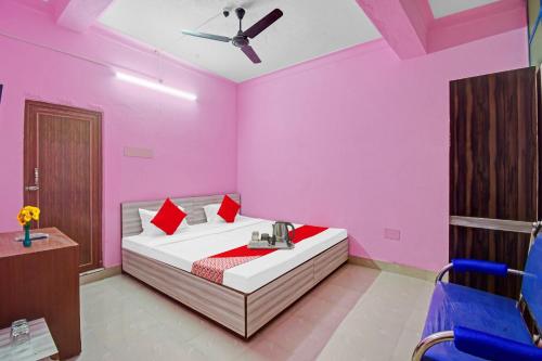 a bedroom with pink walls and a bed with red pillows at Hotel O New Orchid Inn in Kolkata