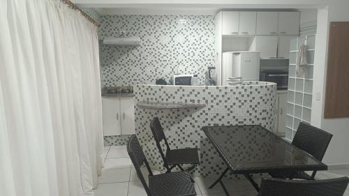 a kitchen with a table and chairs in a room at Apartamento Golden Beach Guarujá in Guarujá