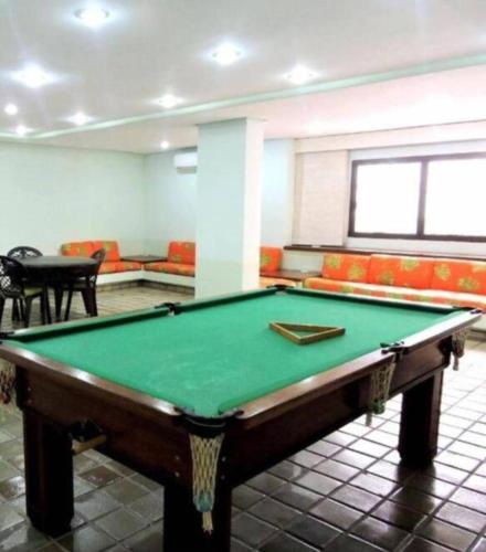 a pool table in a room with couches at Apartamento Golden Beach Guarujá in Guarujá