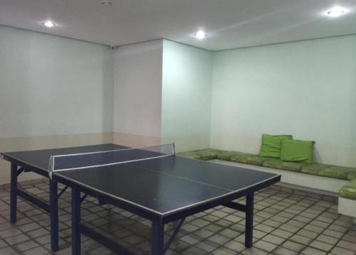a ping pong table in a room with a couch at Apartamento Golden Beach Guarujá in Guarujá