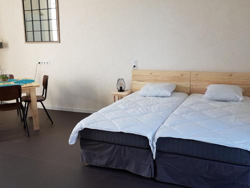 una camera da letto con un letto e un tavolo con una sedia di Presbytère écorénové avec terrasse et vue sur étang, proche Parc Naturel Régional de la Brenne - FR-1-591-180 a Lingé
