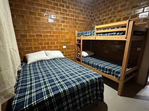a room with two bunk beds and a brick wall at Sua casa na serra in Bezerros