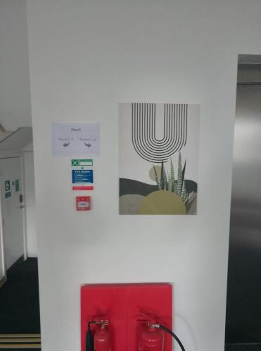 a white wall with two pictures and a red cabinet at Station House One Bedroom Aparthotel - free parking! in Scunthorpe