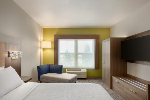 a hotel room with a bed and a chair and a window at Holiday Inn Express- West Sacramento by IHG in West Sacramento