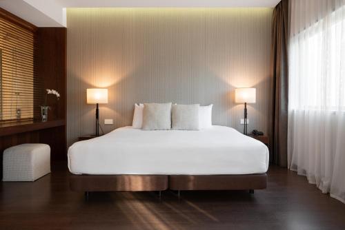 a bedroom with a large white bed with two lamps at Eurostars Mar de Vigo in Vigo