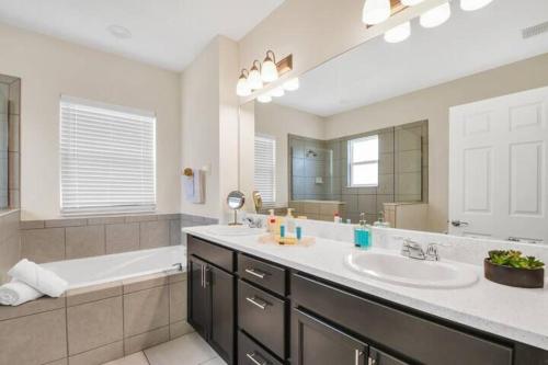 a bathroom with a sink and a bath tub and a sink at Stylish 5-Bedroom Villa - Perfect Disney Getaway! in Davenport