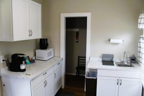a kitchen with white cabinets and a sink and a microwave at Peaceful Family Retreat with Games and Glamping! in Livingston