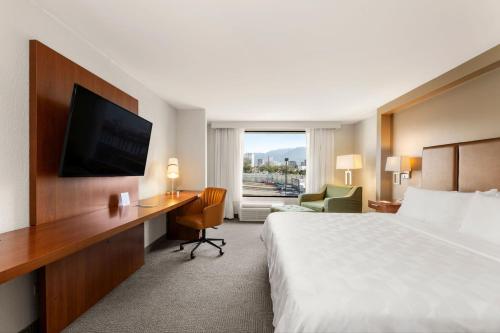 a hotel room with a bed and a desk with a television at Holiday Inn San Jose La Sabana by IHG in San José