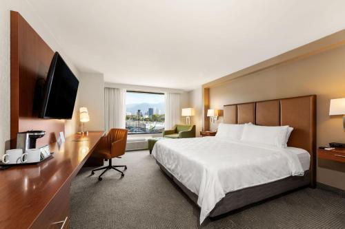 a hotel room with a bed and a desk and a television at Holiday Inn San Jose La Sabana by IHG in San José