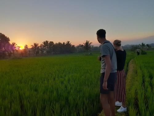 a couple standing in a field watching the sunset at Bello Bungalow in Batukliang