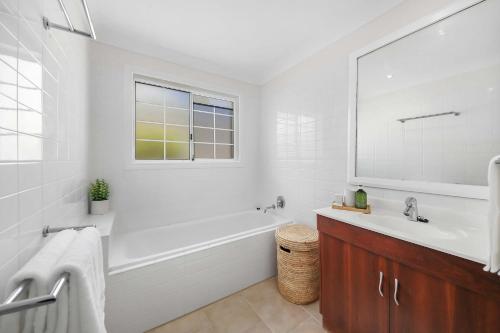 a white bathroom with a tub and a sink at The Pacific - Absolute Beachfront in Buddina in Buddina