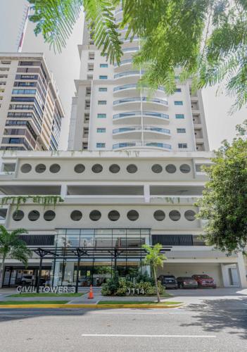 a large white building with tall buildings in the background at Escape Apartments, Balcony, Pool, Gym & Spa in La Julia in Santo Domingo