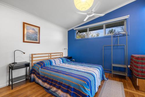 a blue bedroom with a bed and a window at Korogoro Beach House in Hat Head