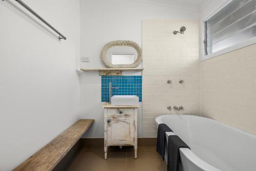 a bathroom with a tub and a sink and a mirror at Korogoro Beach House in Hat Head