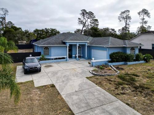 una casa azul con un coche aparcado en la entrada en 4BR 3BA Home with Pool 7mins from Springs, en Weeki Wachee