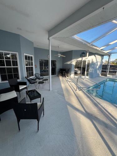Un patio con piscina, mesas y sillas. en 4BR 3BA Home with Pool 7mins from Springs, en Weeki Wachee