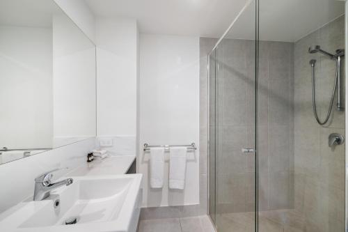 a white bathroom with a sink and a shower at North Shore Oceanside Kawana in Kawana Waters
