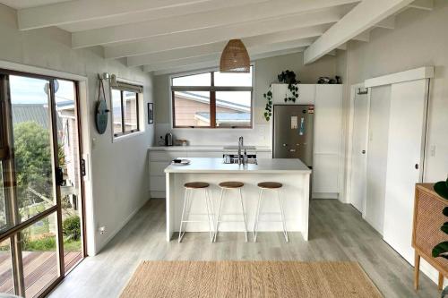 a kitchen with a sink and two bar stools at Tideview Cottage - Incredible Views - Tairua in Tairua