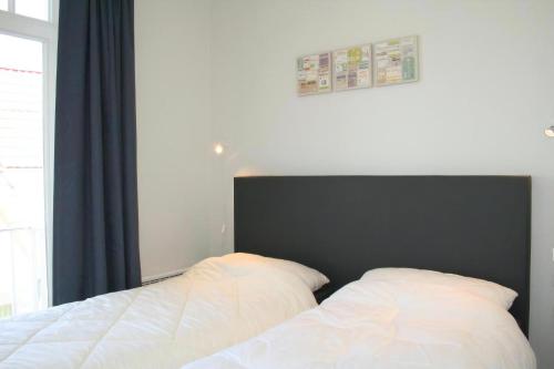 2 Betten in einem Schlafzimmer mit einem schwarzen Kopfteil in der Unterkunft Albatros B1 in De Haan