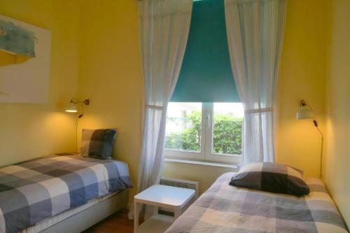 a bedroom with two beds and a window at Albatros C0 in De Haan