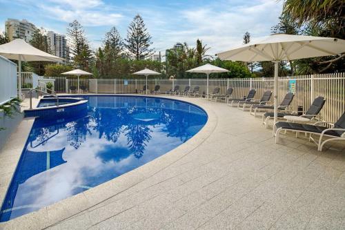 a large swimming pool with chairs and umbrellas at Xanadu Escape - Seaside Resort near Surfers Paradise in Gold Coast