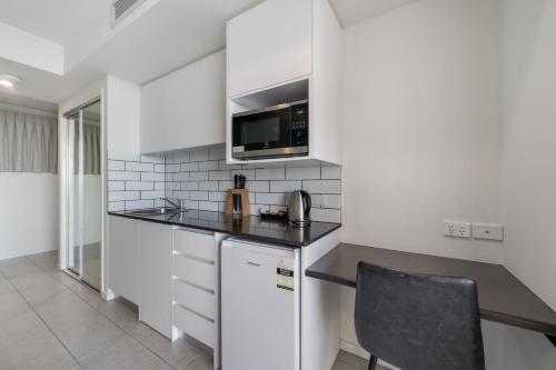 a kitchen with a counter top and a microwave at North Shore Oceanside Kawana in Kawana Waters