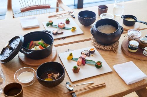 a wooden table topped with bowls and plates of food at SONEKA in Kitahiroshima