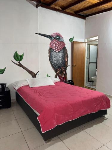 a bedroom with a large red bed with a bird head at EcoHotel Colibrí Salento in Luna Park