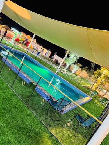 a group of chairs next to a swimming pool at night at Valley View farm in Maghribīyah