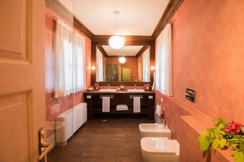 a bathroom with two sinks and a toilet and a mirror at Palazzo Castiglioni Luxury Suites in Mantova